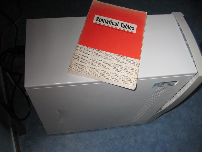 You see a picture of a book labelled ‘statistical tables’, positioned on top of a computer mini-tower.